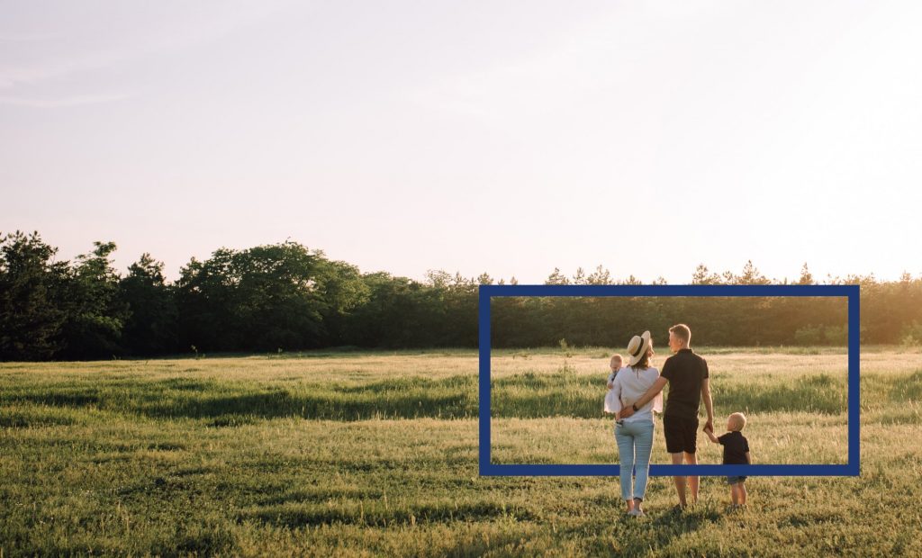 A family holding hands, standing in a field.